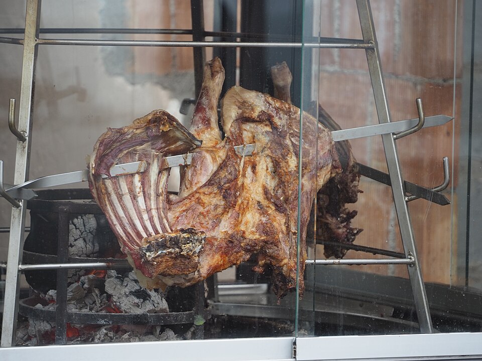 Cretan antikristo lamb propped facing an open fire on skewers