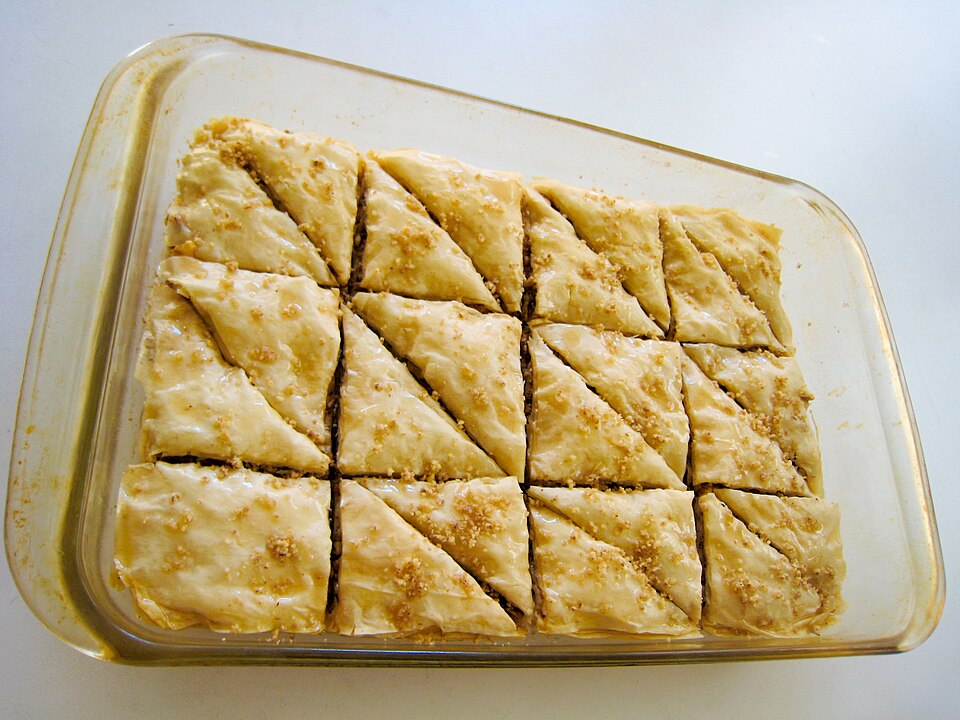 Diamond-cut baklava pieces glossy with honey syrup, studded with walnuts and a clove