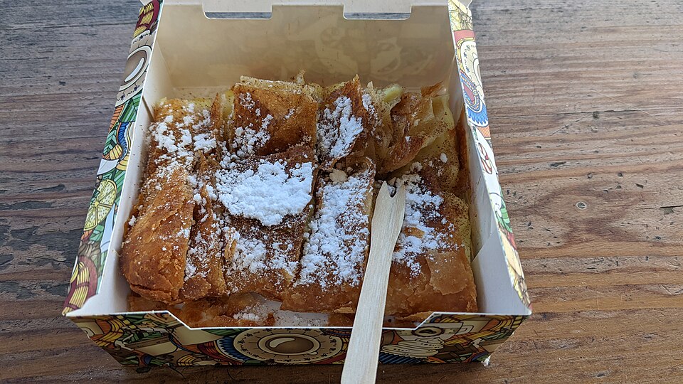 Squares of bougatsa custard pastry dusted with icing sugar and cinnamon