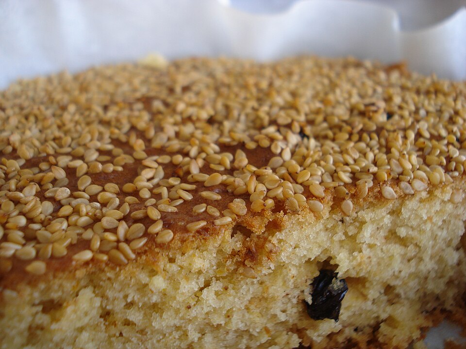 A sliced Greek fanouropita spice cake, dusted with cinnamon