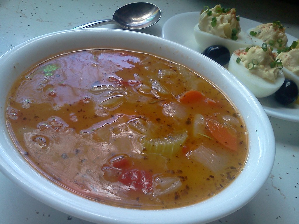 A bowl of thick Greek white bean soup with carrot and celery, olive oil pooled on the surface
