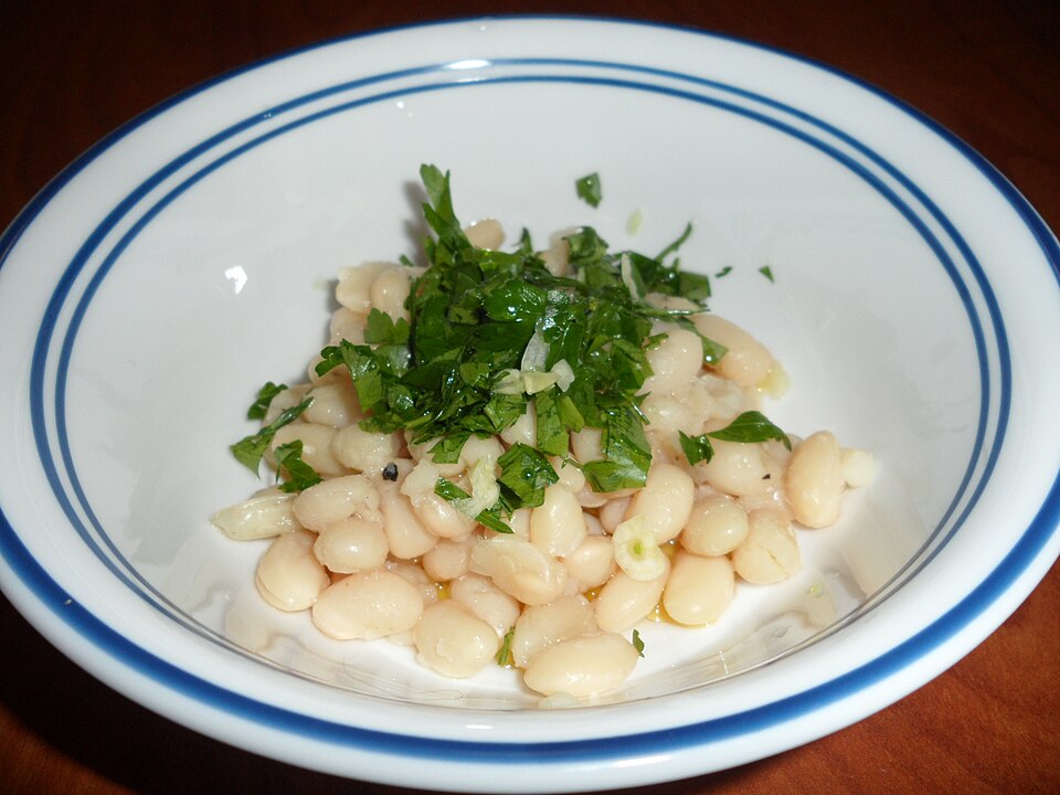 A bowl of Greek fasolia salata white bean salad with red onion and parsley