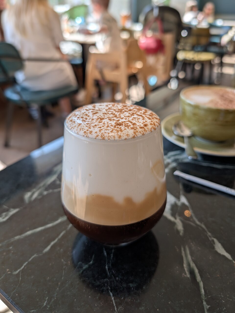 A glass of Greek freddo cappuccino with a thick cold milk foam cap