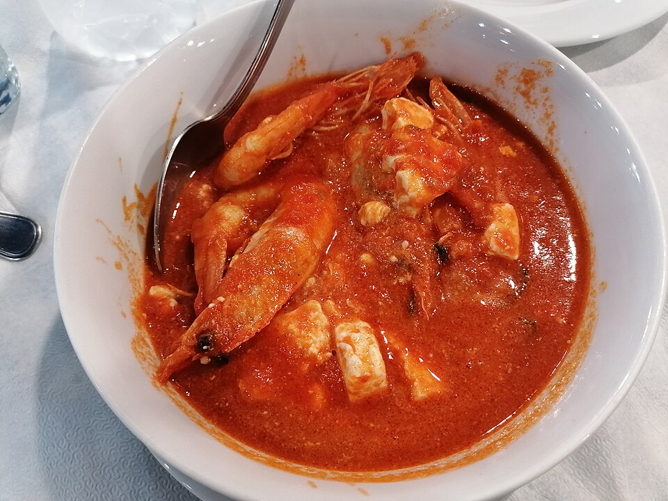 Prawns baked in tomato sauce with melting feta and parsley in a small pan