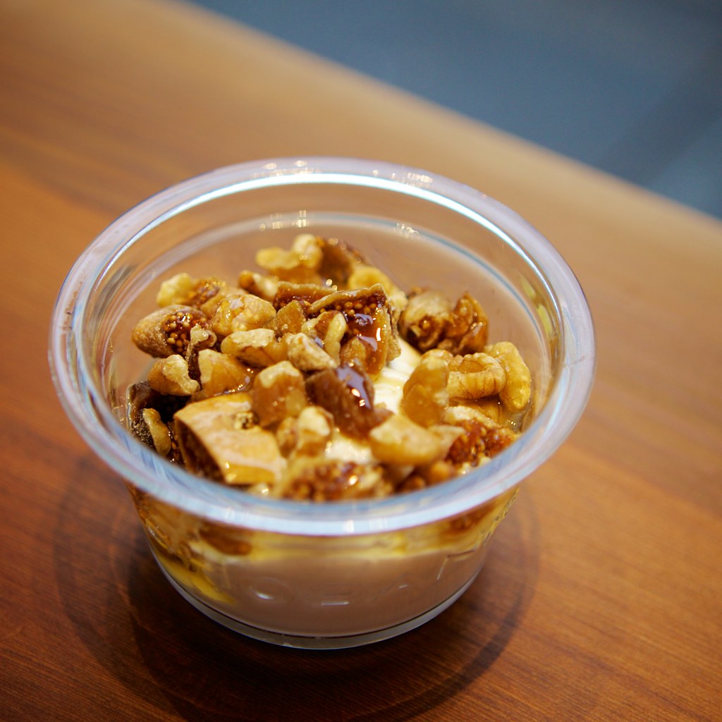 A bowl of thick Greek yogurt topped with honey and crushed walnuts