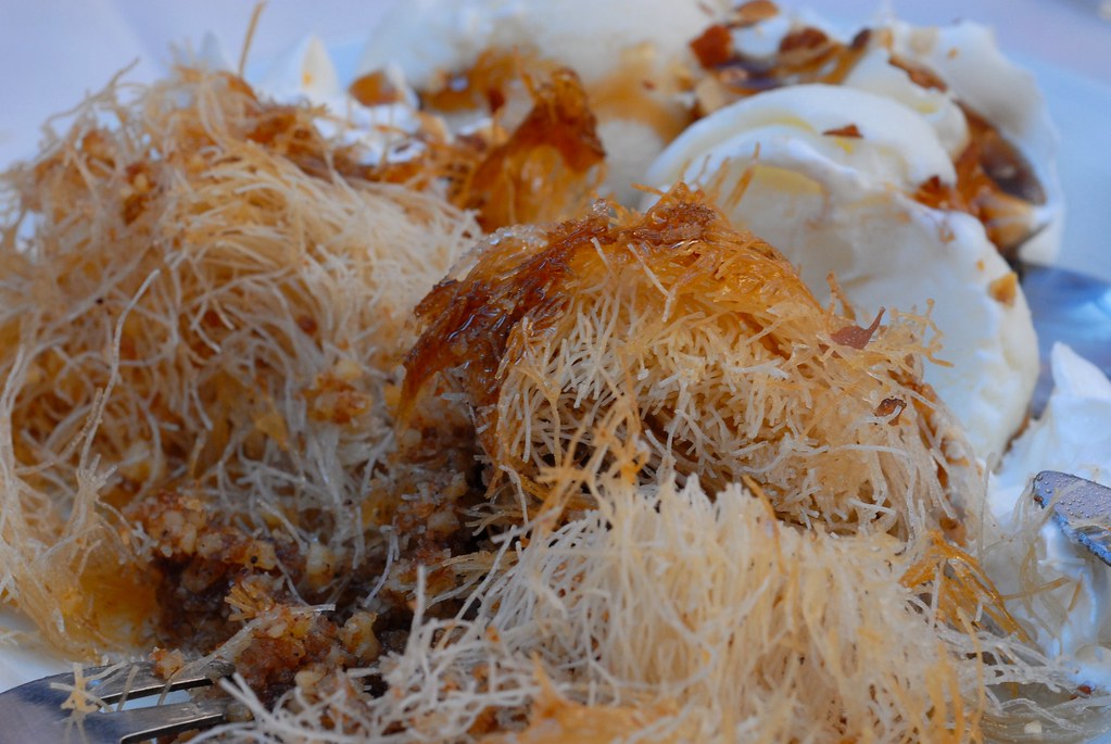 A tray of Greek kataifi shredded pastry and walnut rolls in syrup