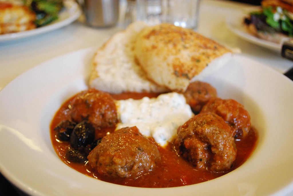 A plate of golden brown Greek meatballs with lemon wedges and fresh mint