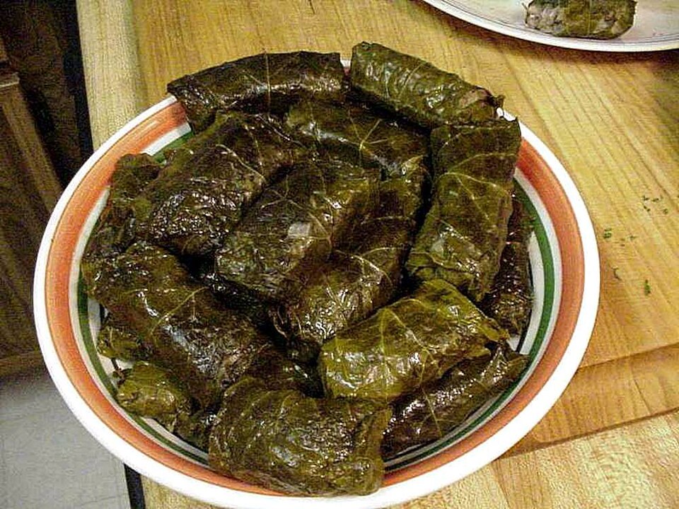 Cypriot koupepia stuffed vine leaves arranged on a plate with lemon