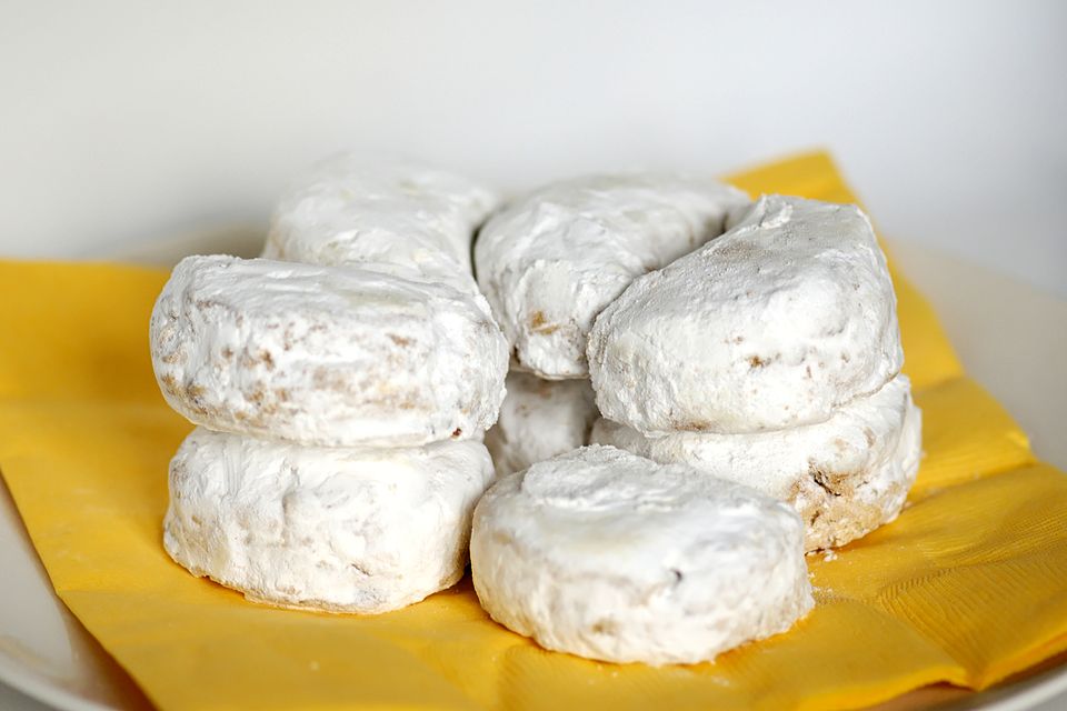 Greek kourabiedes cookies buried under thick icing sugar on a plate