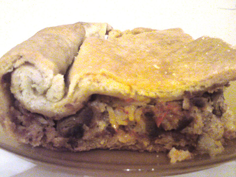 A slice of Greek kreatopita meat pie showing layered phyllo and filling