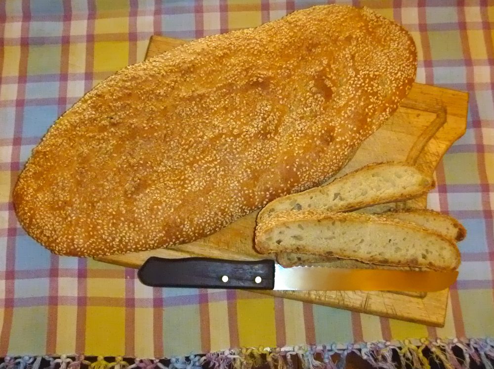 A flat oval Greek lagana bread topped with sesame seeds