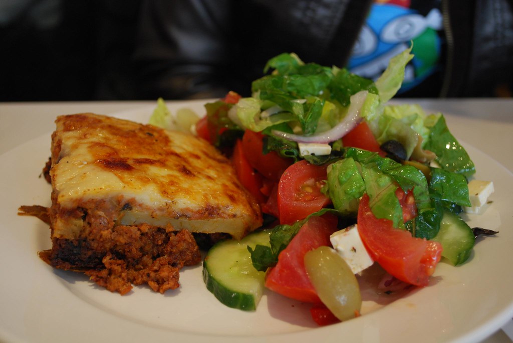 A tray of Greek moussaka with a browned bechamel top, one square lifted out