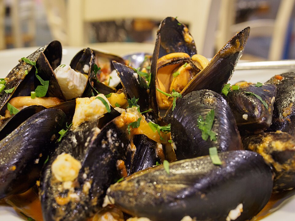 A pan of Greek mydia saganaki mussels in tomato and feta sauce