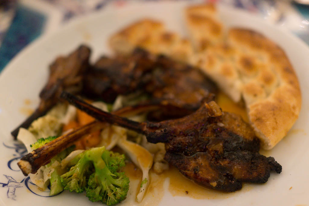 Charred Greek paidakia lamb chops on a grill with lemon and oregano