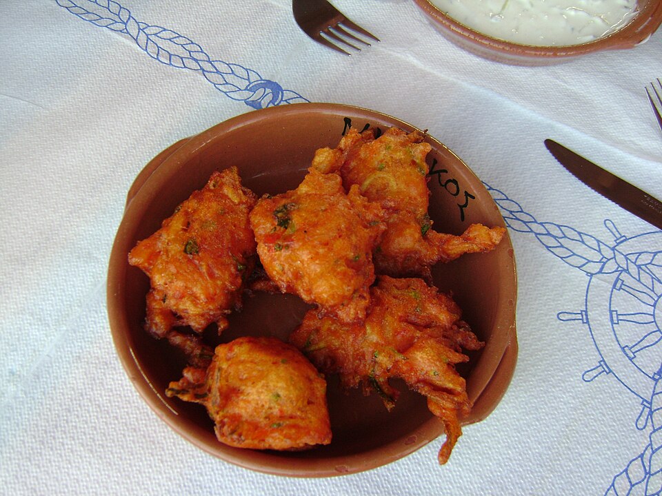Crisp Rhodian chickpea fritters piled on paper with lemon wedges
