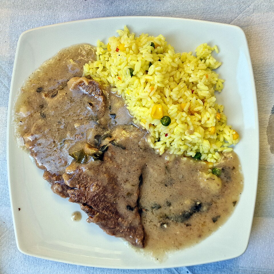 Thin slices of veal in a pale garlic and parsley sauce with rice alongside
