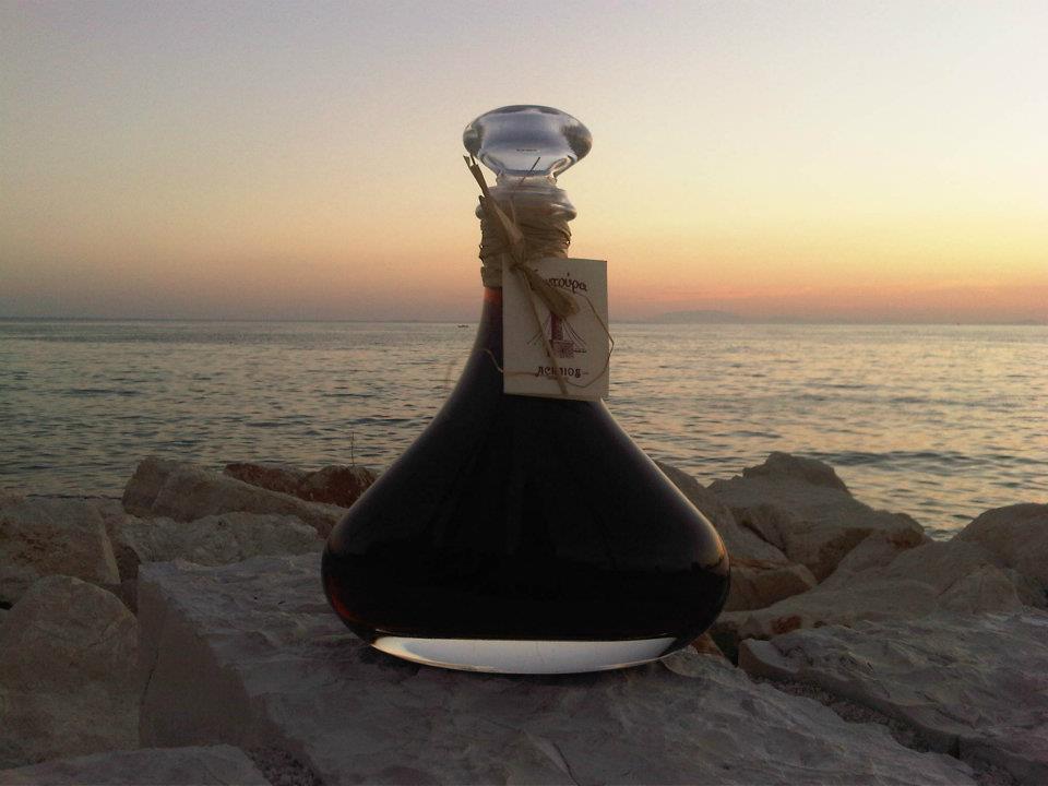 A small glass of Patras tentoura liqueur beside cinnamon bark and cloves