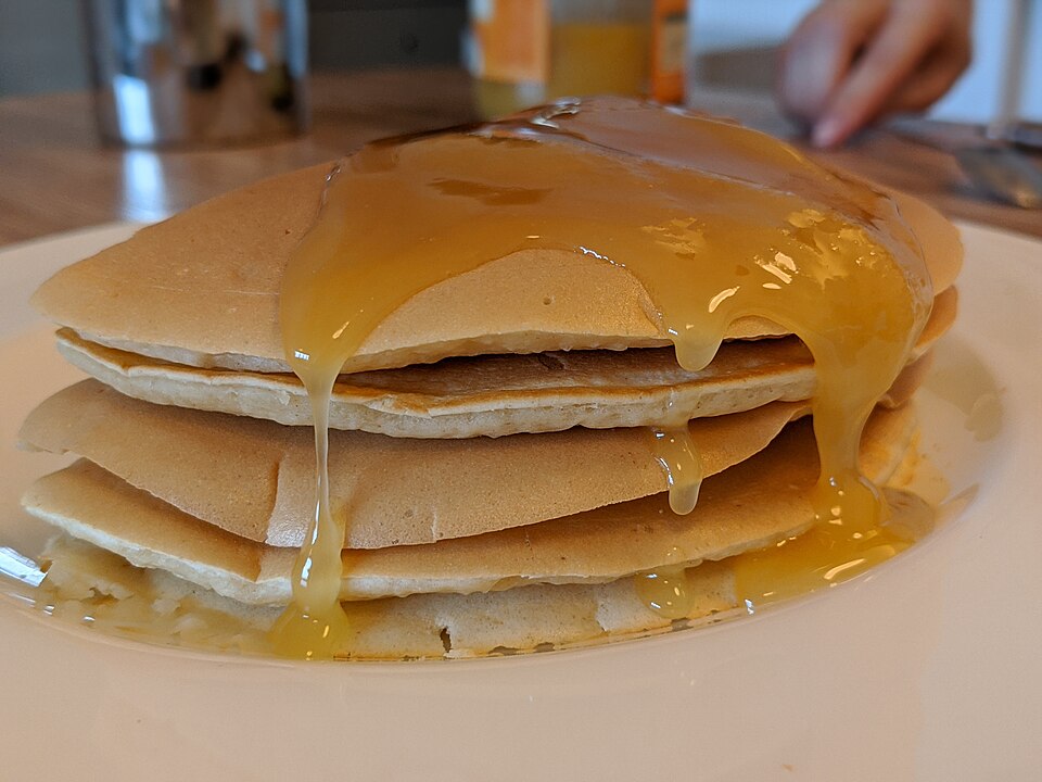 A stack of Greek tiganites pancakes drizzled with honey and walnuts